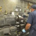 Machinist operating a lathe machine in an industrial workshop