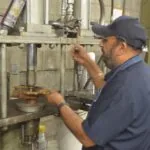 Technician in blue uniform operating industrial testing equipment in workshop