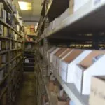 Warehouse aisle with metal shelving units stocked with packaged items on both sides