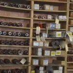 Wooden shelving unit displaying various automotive bearings, pulleys, and electrical components with labeled boxes and packages