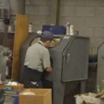 Technician working at industrial equipment in workshop with concrete block walls and various tools and machinery