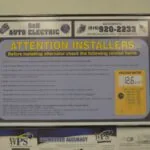 Framed instructional sign from S&N Auto Electric displaying alternator installation checklist with voltage meter display
